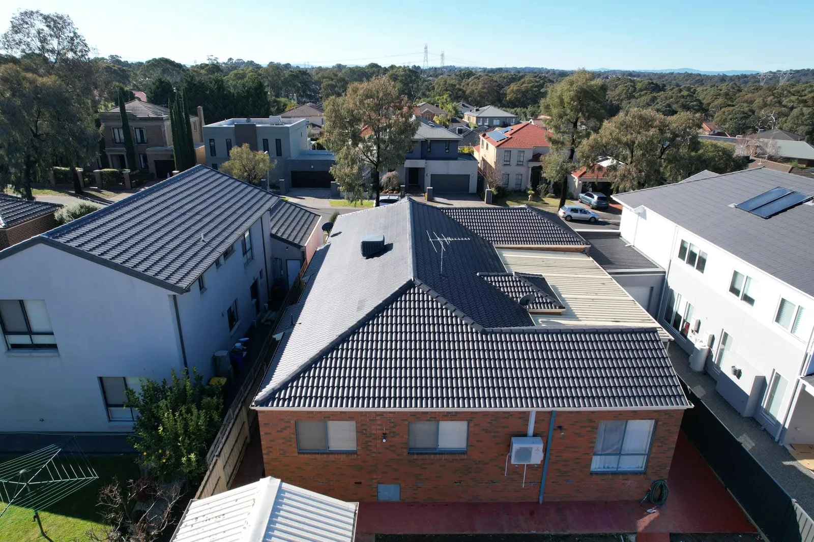 Aerial view of a brick home with a newly restored charcoal tile roof, surrounded by neighbouring properties